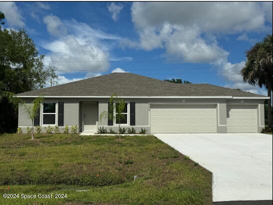 523 Town Rd SW, Palm Bay, FL 32908 - ranch-style house with an attached garage, concrete driveway, stucco siding, and a front lawn