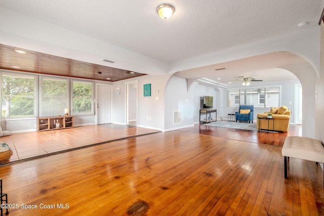 unfurnished living room featuring ceiling fan, a textured ceiling, and light wood-type flooring