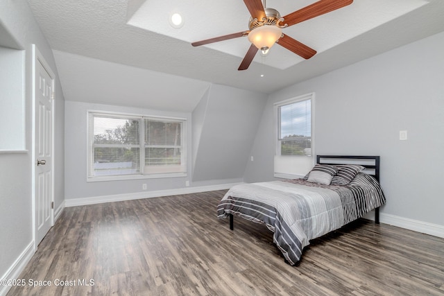 bedroom with ceiling fan, dark hardwood / wood-style flooring, lofted ceiling, and a textured ceiling