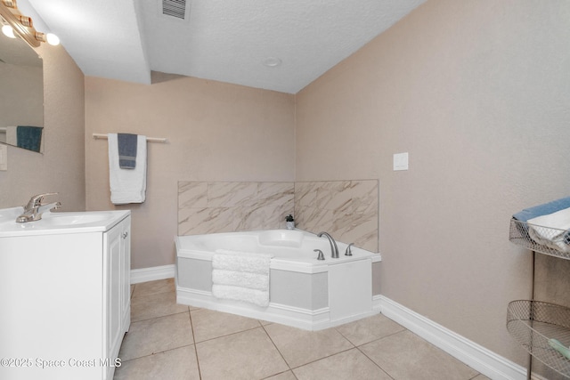 bathroom featuring tile patterned flooring, vanity, a tub to relax in, and a textured ceiling