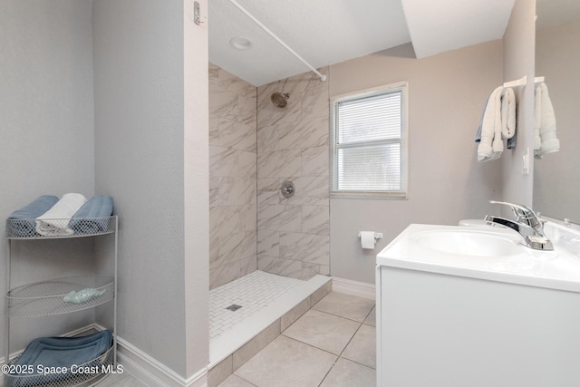 bathroom with a tile shower, tile patterned flooring, and vanity