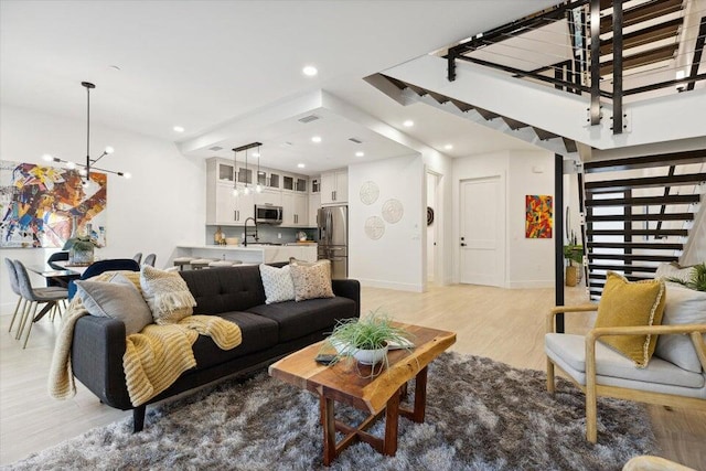 living room featuring light hardwood / wood-style floors, sink, and an inviting chandelier