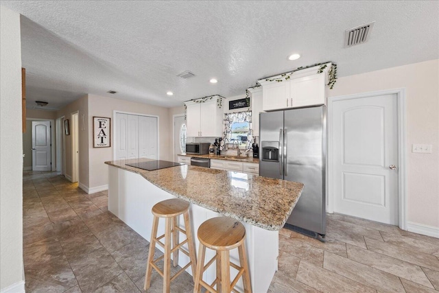 kitchen featuring a breakfast bar area, appliances with stainless steel finishes, white cabinetry, and a kitchen island