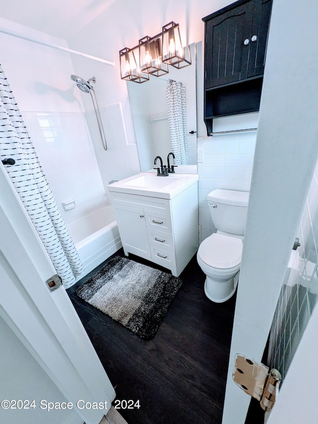 full bathroom featuring vanity, hardwood / wood-style flooring, toilet, tile walls, and shower / tub combo with curtain