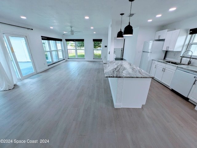 kitchen featuring white appliances, backsplash, white cabinets, sink, and decorative light fixtures