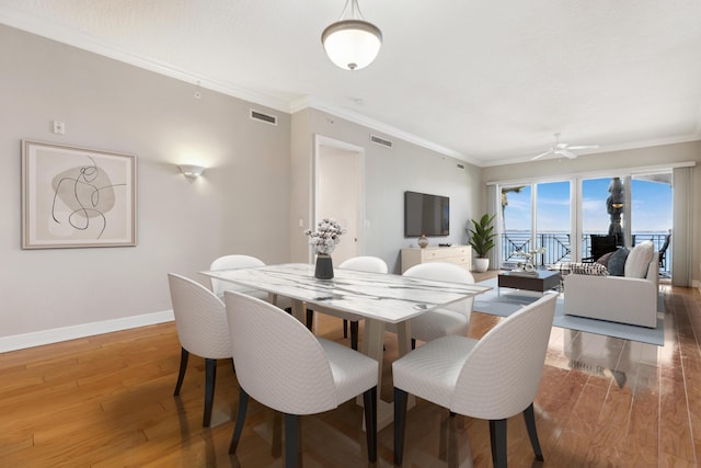 dining space with wood-type flooring, ceiling fan, and crown molding