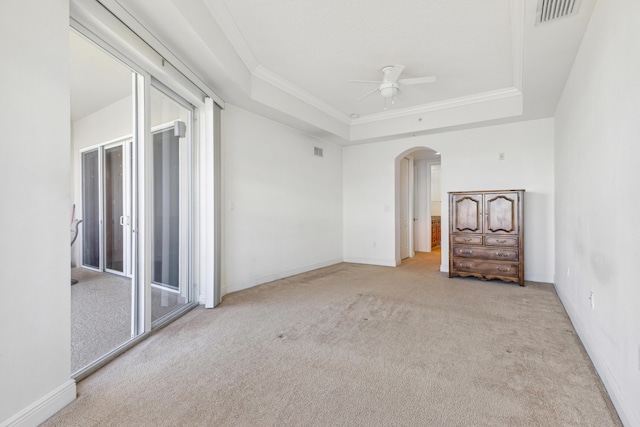 carpeted empty room with a raised ceiling, ceiling fan, and ornamental molding