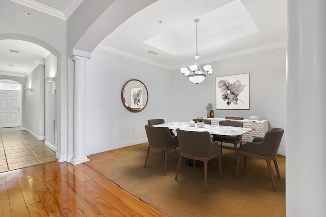 dining room with wood-type flooring, crown molding, a chandelier, and ornate columns