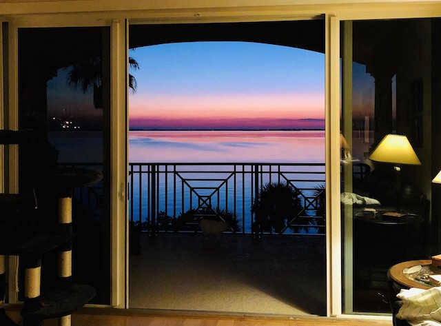 balcony at dusk featuring a water view