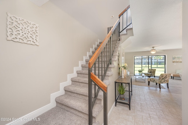 staircase featuring ceiling fan