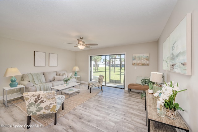 living room with light wood-type flooring, ceiling fan, and a textured ceiling