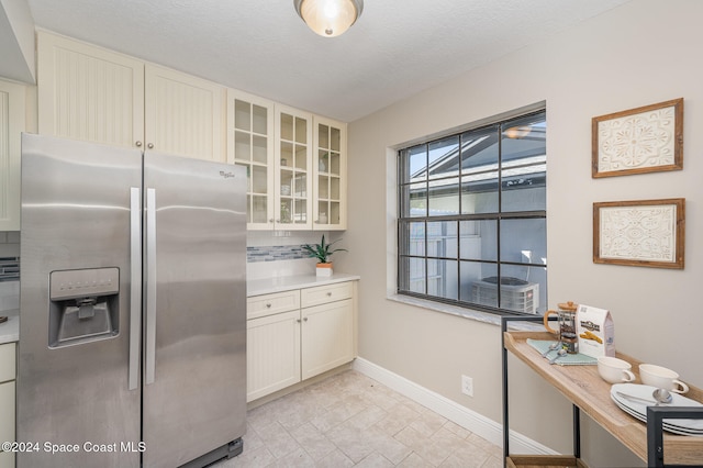 kitchen with stainless steel refrigerator with ice dispenser, white cabinets, and decorative backsplash