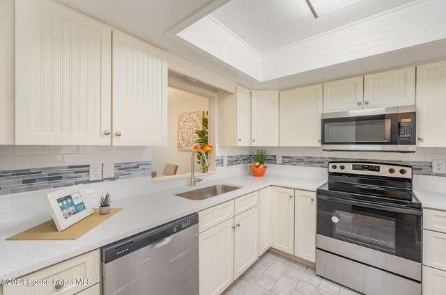 kitchen with light tile patterned floors, appliances with stainless steel finishes, backsplash, and sink