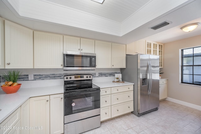 kitchen featuring stainless steel appliances, cream cabinets, and tasteful backsplash