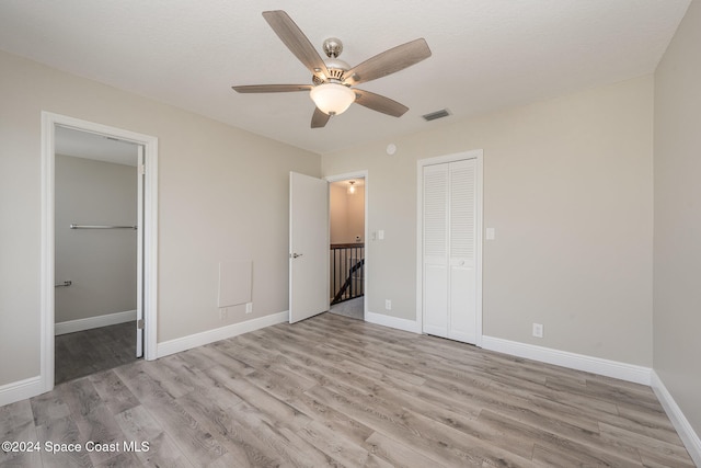 unfurnished bedroom featuring ceiling fan, light hardwood / wood-style floors, and a closet