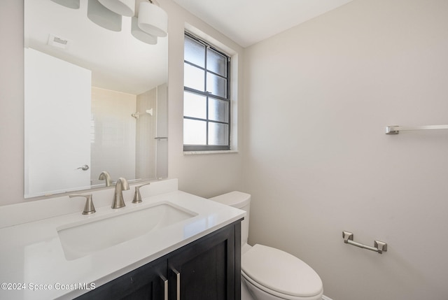 bathroom featuring a shower, toilet, and vanity