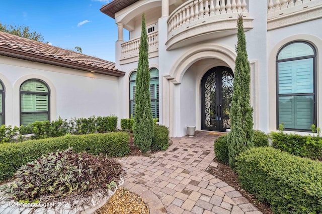 view of exterior entry featuring a balcony and french doors