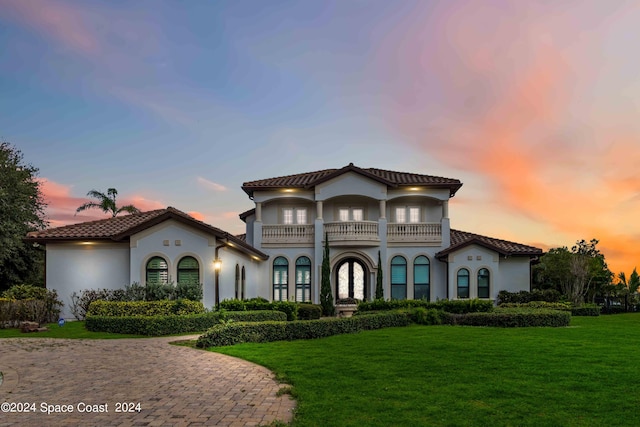 mediterranean / spanish-style home featuring a balcony and a yard