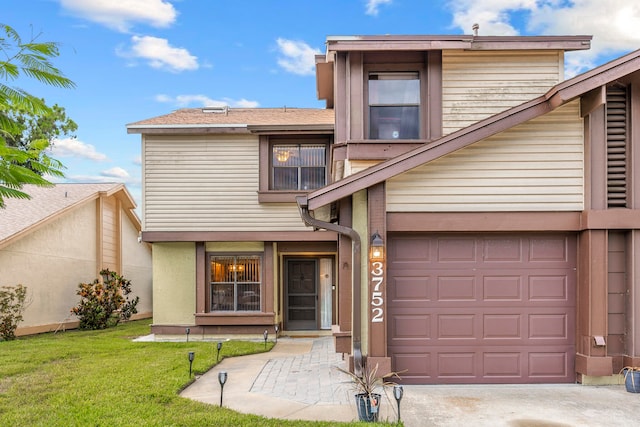 view of property featuring a garage and a front lawn