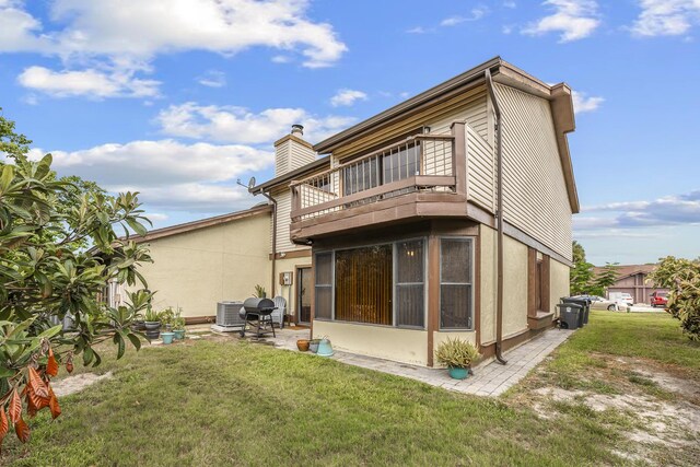 back of property featuring a balcony, a patio area, central AC unit, and a yard