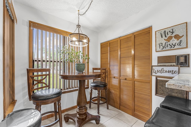 dining room with baseboards, a textured ceiling, an inviting chandelier, and light tile patterned floors