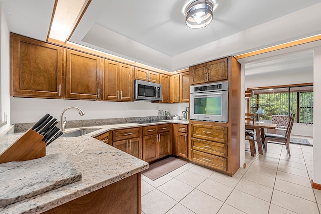 kitchen featuring appliances with stainless steel finishes, light tile patterned floors, light stone countertops, and sink