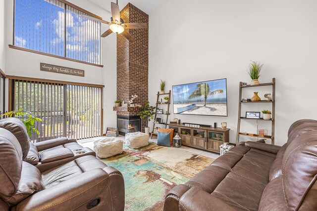 living room featuring brick wall, a brick fireplace, ceiling fan, and a high ceiling