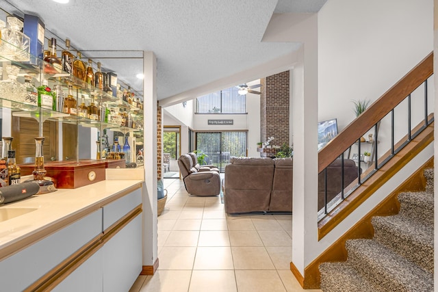 bar featuring light tile patterned floors, stairway, a textured ceiling, and a ceiling fan