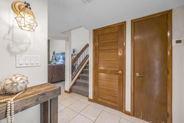 hall featuring light tile patterned floors and a textured ceiling