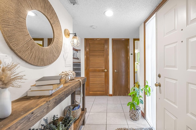 foyer featuring a textured ceiling, stairway, and light tile patterned flooring