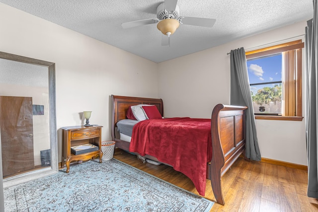 bedroom featuring a ceiling fan, a textured ceiling, baseboards, and hardwood / wood-style floors