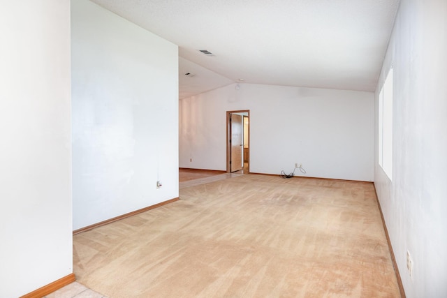 carpeted spare room featuring vaulted ceiling