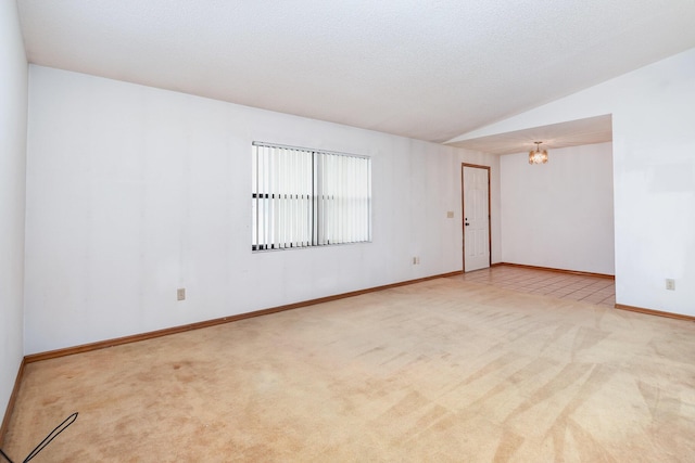 unfurnished room featuring light carpet, lofted ceiling, and a chandelier