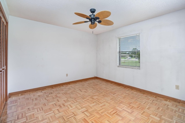 empty room with ceiling fan, light parquet flooring, and a textured ceiling