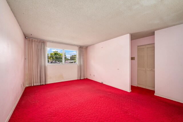 carpeted empty room featuring a textured ceiling and baseboards