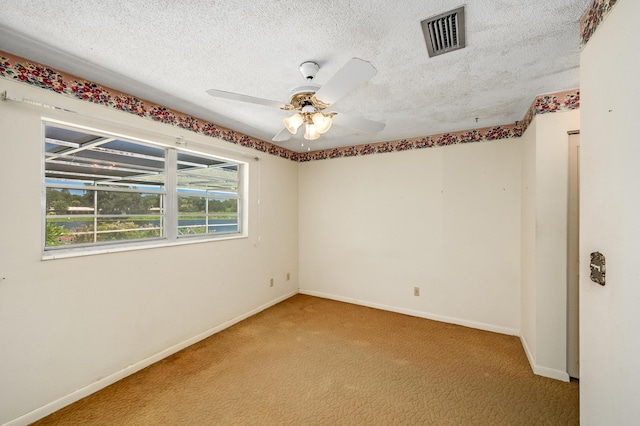 spare room with visible vents, baseboards, ceiling fan, carpet flooring, and a textured ceiling