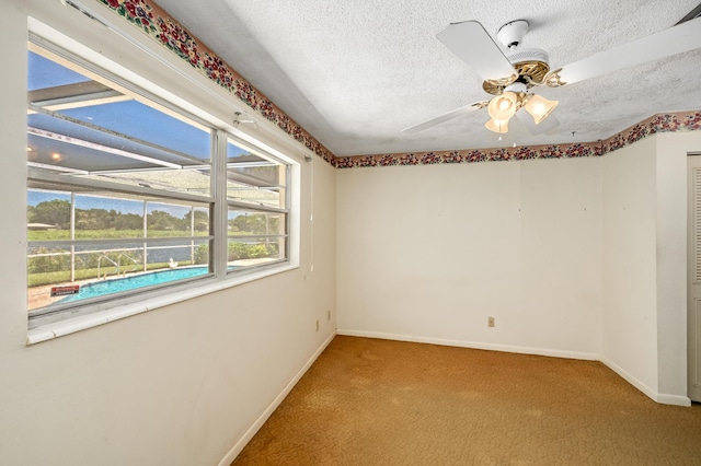 spare room with carpet flooring, a textured ceiling, baseboards, and a ceiling fan