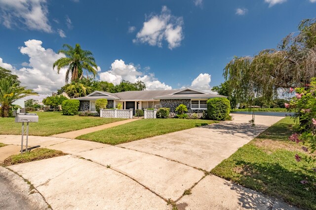 view of front facade featuring stone siding, concrete driveway, and a front lawn