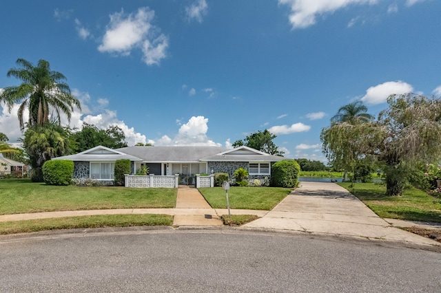 view of front of home with a fenced front yard, concrete driveway, and a front lawn