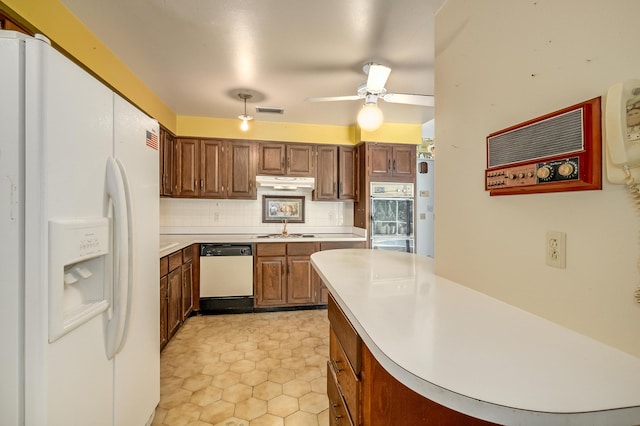 kitchen with a ceiling fan, under cabinet range hood, tasteful backsplash, white appliances, and light countertops