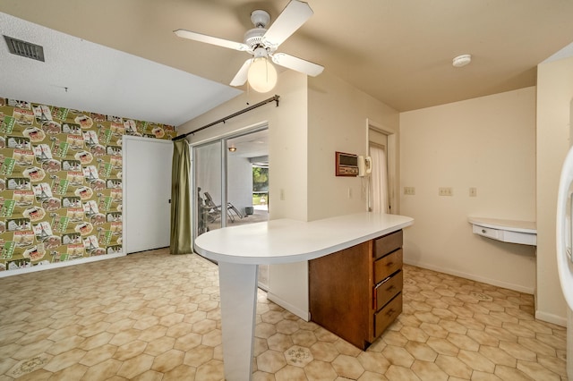 kitchen featuring visible vents, ceiling fan, baseboards, light countertops, and brown cabinetry