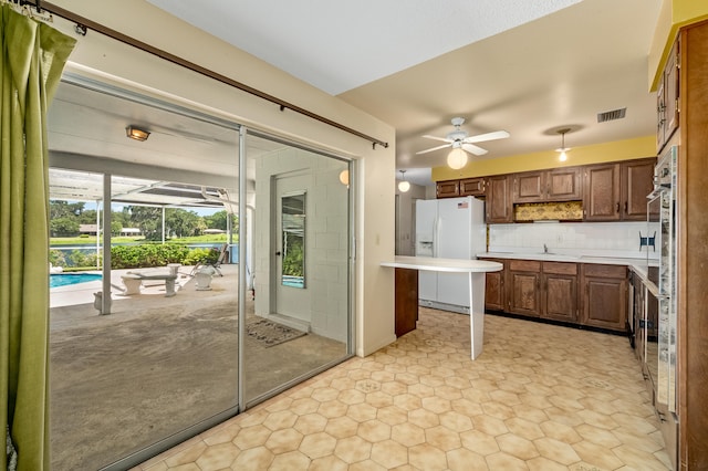 kitchen with backsplash, white fridge with ice dispenser, light tile patterned floors, and ceiling fan