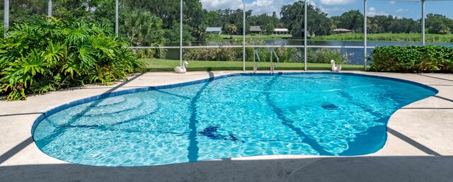 pool with glass enclosure, a yard, and a water view