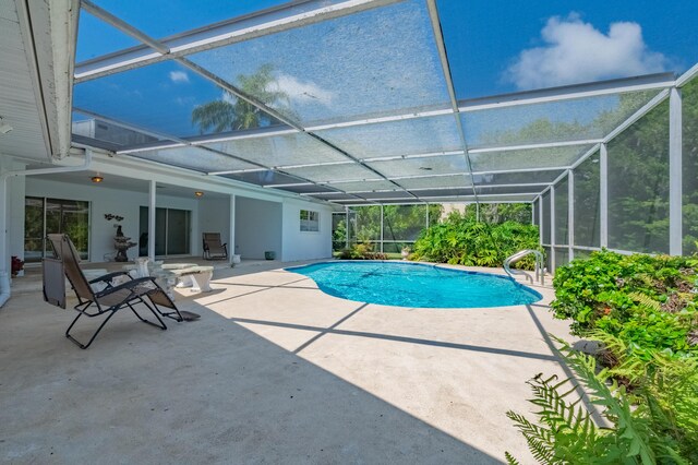 view of swimming pool featuring glass enclosure and a patio area