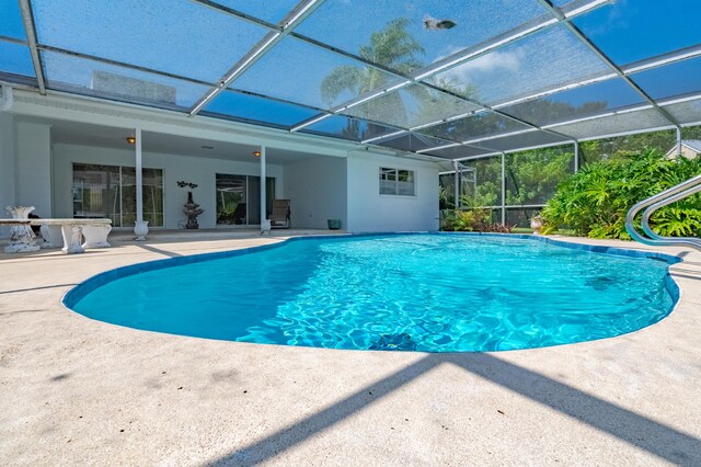 view of pool with glass enclosure and a patio area