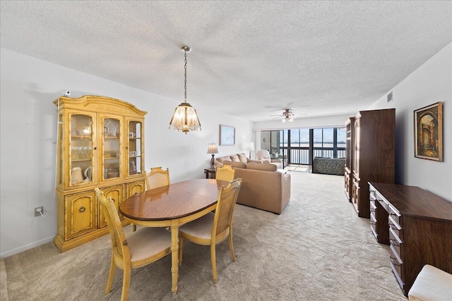 carpeted dining area featuring ceiling fan with notable chandelier and a textured ceiling