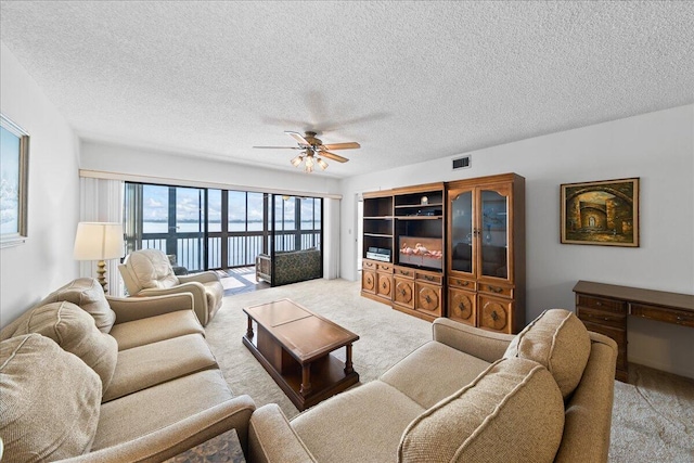 carpeted living room with ceiling fan and a textured ceiling