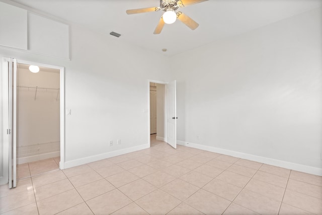 spare room with ceiling fan, light tile patterned flooring, and a high ceiling