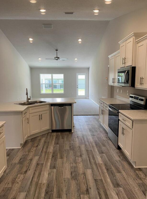 kitchen with sink, white cabinetry, lofted ceiling, dark hardwood / wood-style floors, and appliances with stainless steel finishes