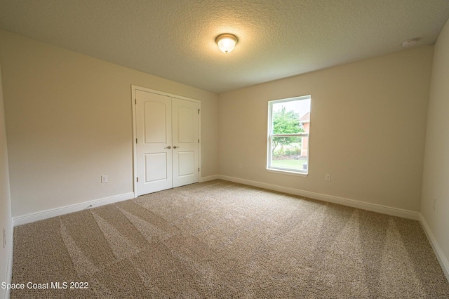 empty room featuring a textured ceiling and carpet